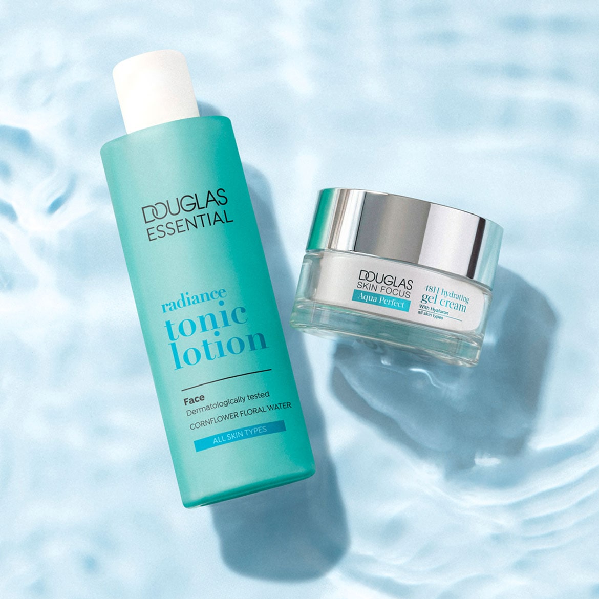 De Douglas Essential Radiance Tonic Lotion en Douglas Skin Focus Aqua Perfect 18H Hydrating Gel Cream, beide in blauwgroene verpakkingen, liggen op een lichtblauwe ondergrond met waterrimpelingen.