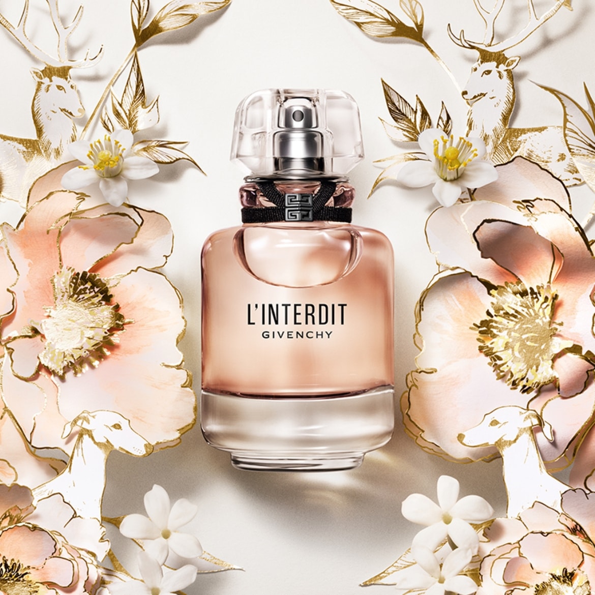 Découvrez L'Interdit de Givenchy, un parfum floral et boisé présenté dans un flacon élégant, entouré de fleurs délicates et de motifs dorés.