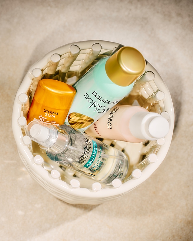 Een mandje gevuld met Douglas producten, waaronder zonnebrandcrème met SPF 50, Salobil zonnebrandolie, Aqua Perfect 2-in-1 hydraterende mist en Douglas Essentials.