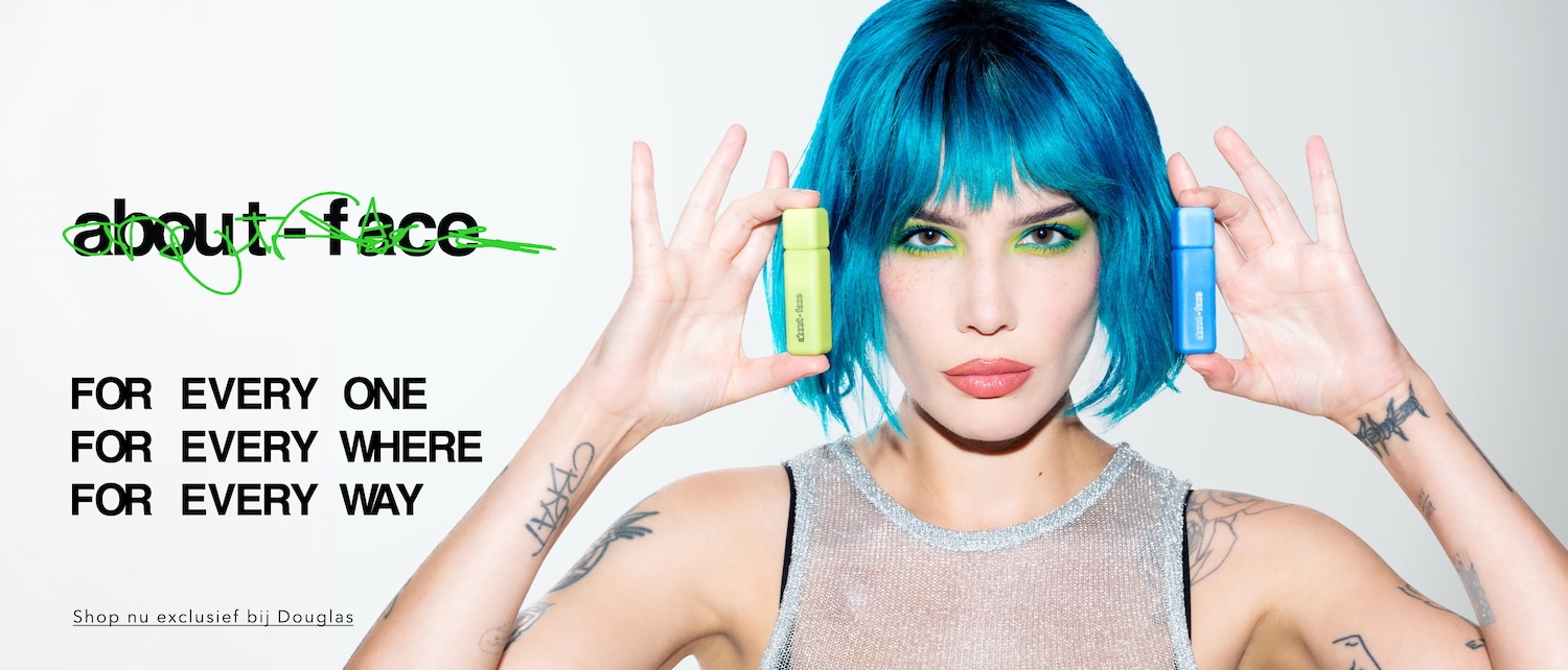 Een vrouw met blauw haar houdt een groene en een blauwe About-Face product vast, met de tekst: 'Voor iedereen, overal, op elke manier'. Shop nu exclusief bij Douglas.