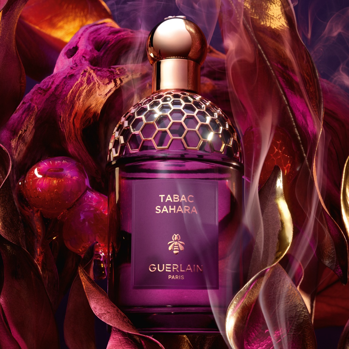 Ontdek Guerlain's Tabac Sahara parfum, gepresenteerd in een paarse flacon met gouden accenten, omringd door decoratieve bladeren en rook.