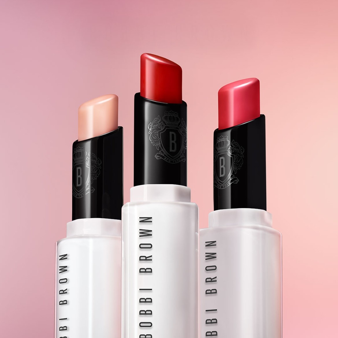 Découvrez les rouges à lèvres Bobbi Brown dans leurs tubes blancs emblématiques, coiffés de noir et offrant une palette de couleurs allant du nude délicat au rouge passion.