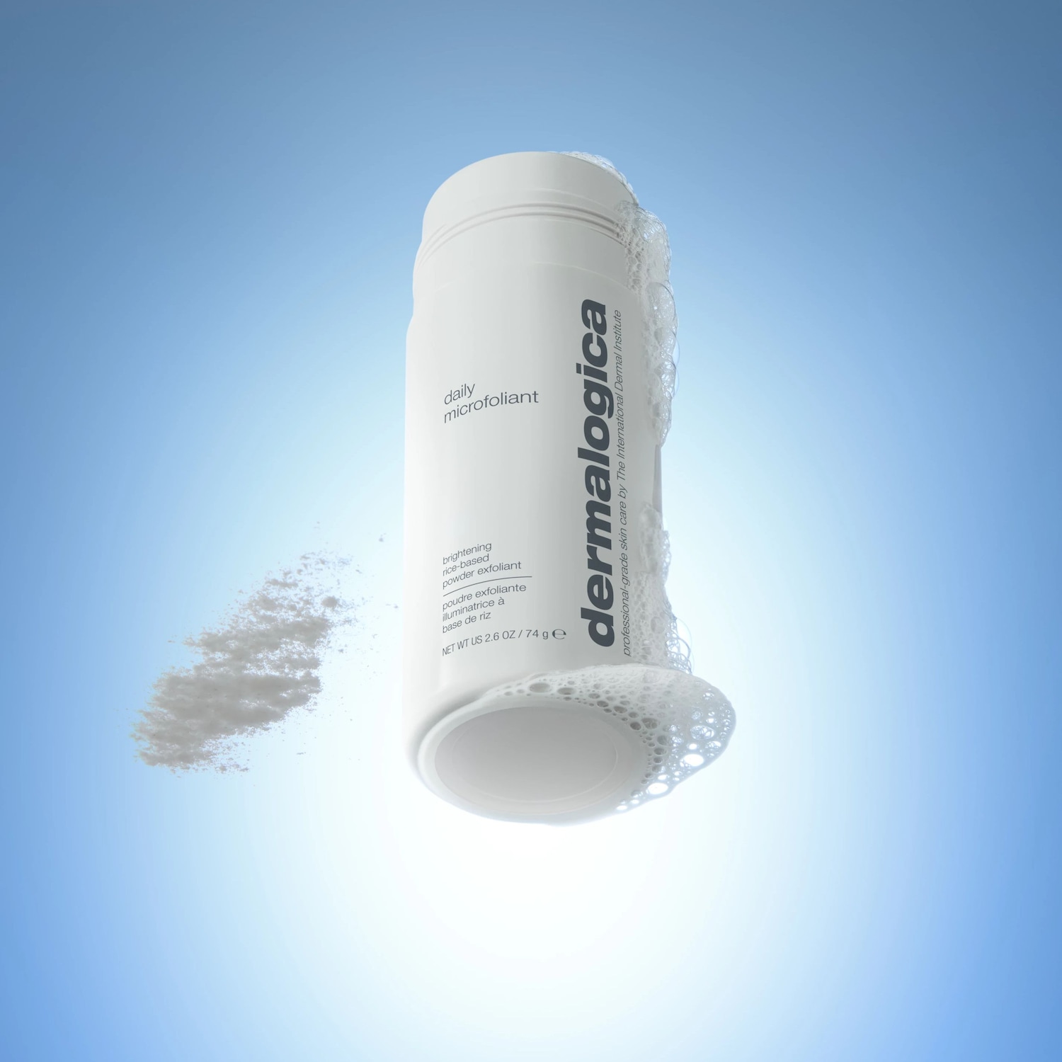 De Dermalogica Daily Microfoliant, een witte fles met zwarte letters, staat rechtop met schuim aan de onderkant en een wolk van wit poeder ernaast, tegen een helderblauwe achtergrond.
