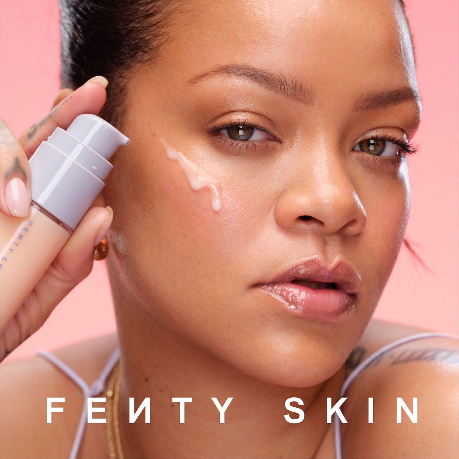 Découvrez Fenty Skin : Rihanna applique un sérum blanc laiteux sur sa peau éclatante, le tout sur un fond rose doux.