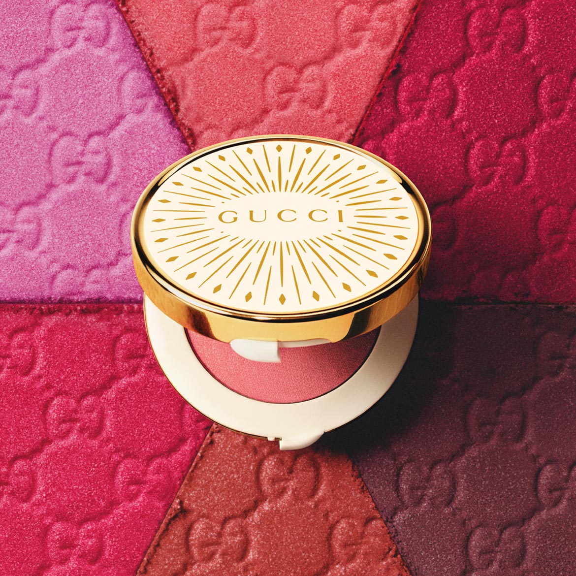 Ontdek de Gucci blush met een gouden verpakking, perfect voor een stralende look, tegen een achtergrond van roze en rode tinten.