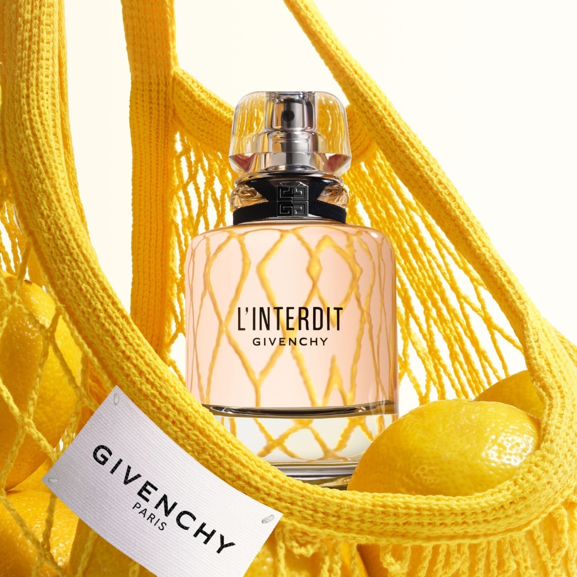 De Givenchy L'Interdit-parfumfles zit in een gele nettas met citroenen, met een wit label met het Givenchy-logo.
