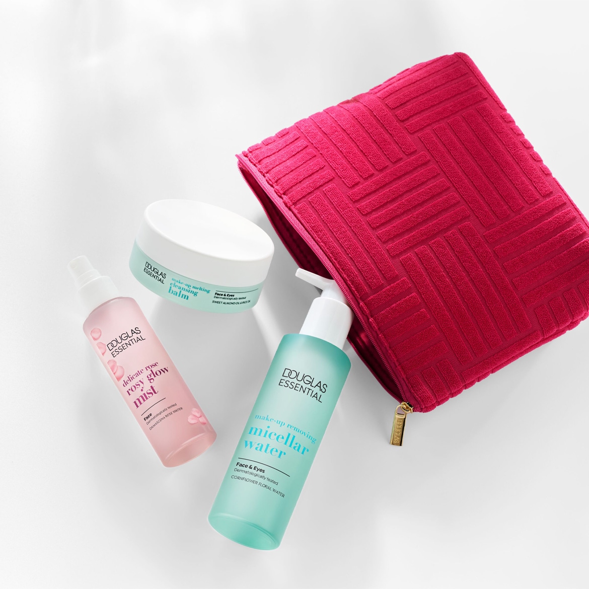 Ontdek de Douglas Essentials collectie: make-up smeltende reinigingsbalsem, delicate rozen glow mist, en micellair water voor een complete gezichtsreiniging, gepresenteerd met een stijlvolle roze toilettas.