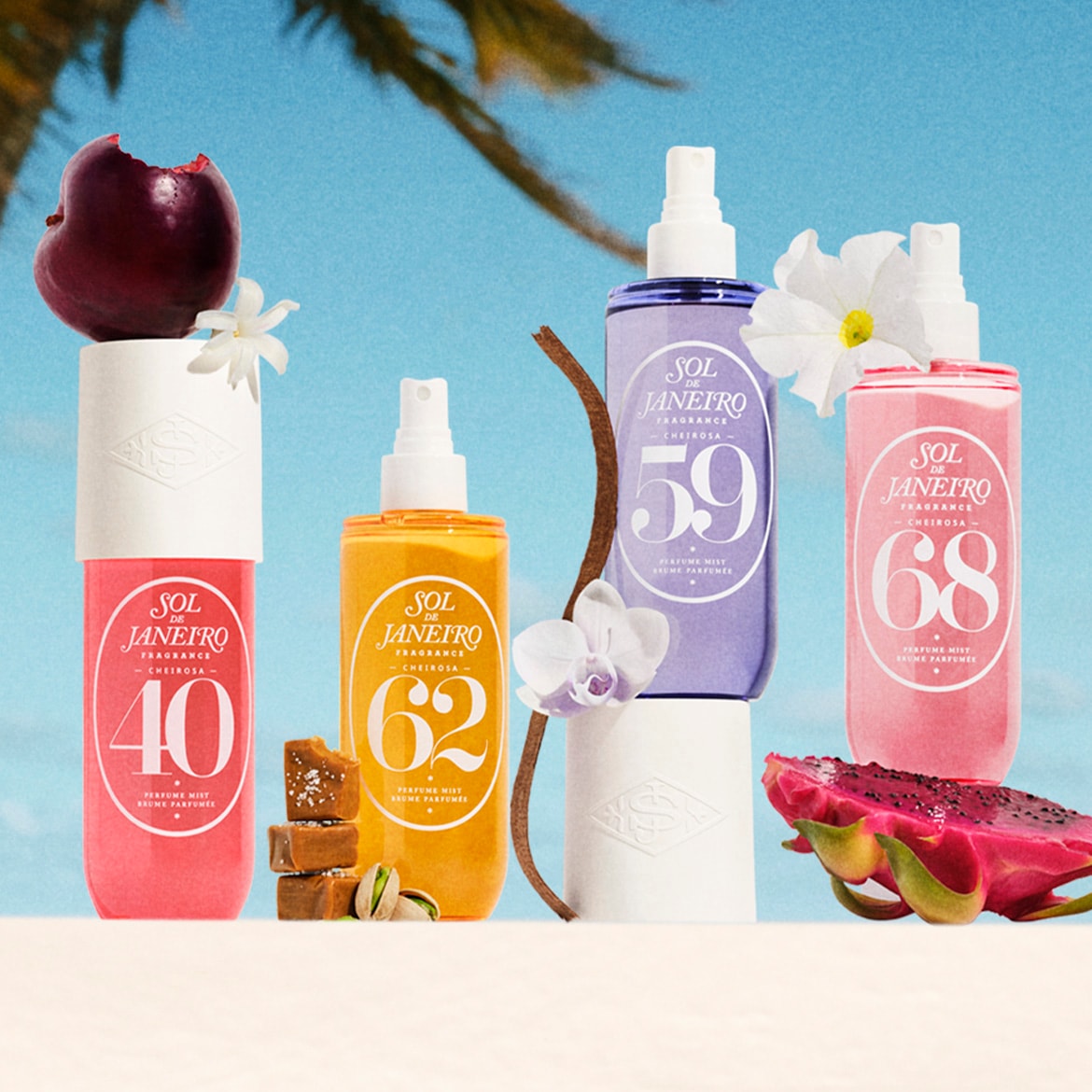 Vier Sol de Janeiro Cheirosa parfumverstuivers in roze, geel, paars en lichtroze, elk met een nummer (40, 62, 59, 68) en omringd door fruit en bloemen, tegen een blauwe lucht met palmbladeren.