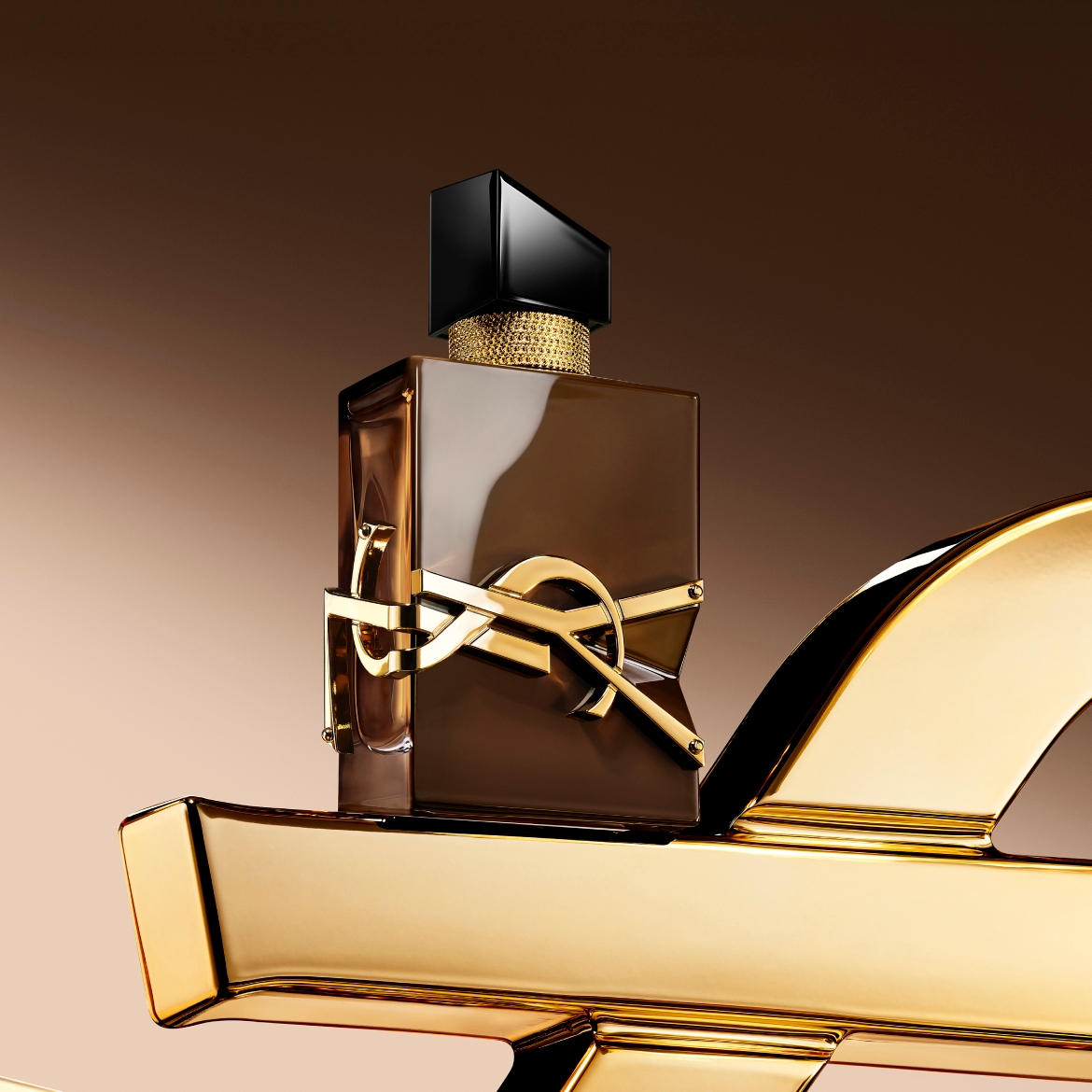 De Libre Le Parfum van Yves Saint Laurent is een amberkleurig parfum in een bruine fles met een gouden YSL-logo en een zwarte dop, staand op een glanzend gouden oppervlak.